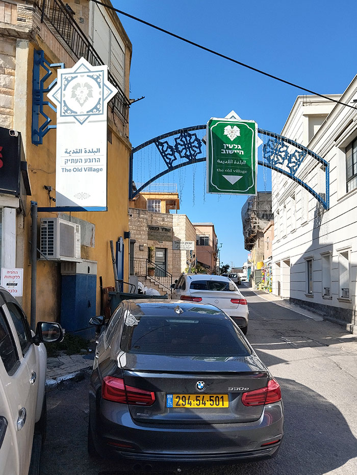 השער עם שלט מאולתר ולצידו משמאל שלט הנושא שם שונה, הרובע העתיק