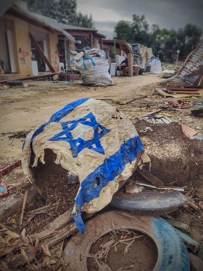 כפר עזה, דצ' 2023. ברקע כבר נראים שקים לפינוי פסולת בניין וגם הדגל מונח בצורה מכוונת – האתר משנה פניו במהירות